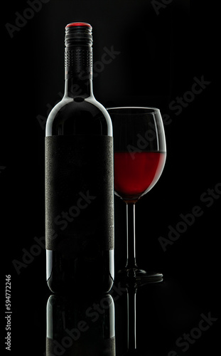 Bottle and the glass of red wine on black background