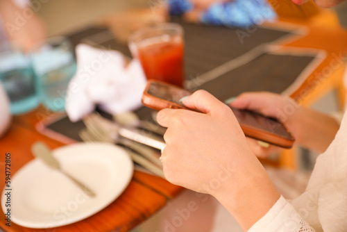 people holding phones at a dining table symbolizes the prevalence of technology in our modern lives, but also the potential distraction and lack of presence in social situations