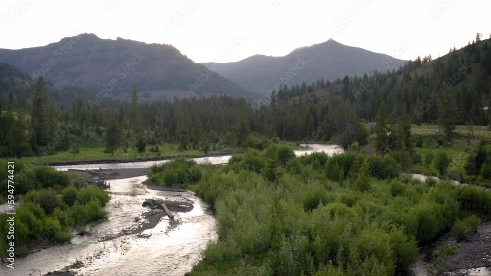 Drone view over a river surrounded by green woods and mountains Drone view over a river surrounded by green woods and mountains