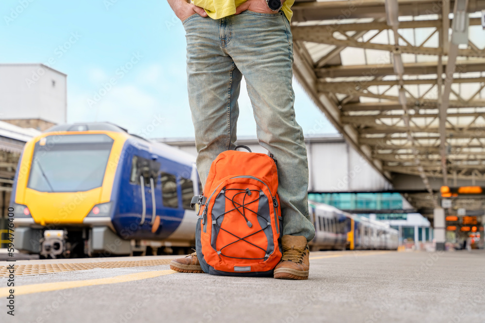 Traveler with a backpack waiting for a train at the train station. Travel concept. Traveler with a backpack waiting for a train at the train station. Travel concept.