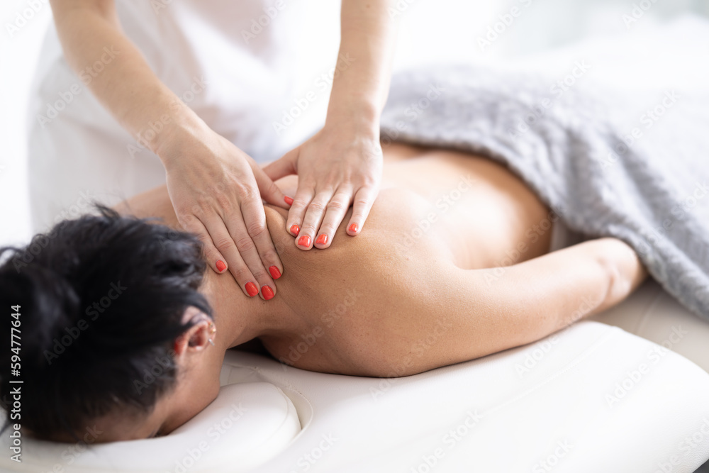 Masseur releases the tension from a stiff shoulder of a female client in the massaging studio Masseur releases the tension from a stiff shoulder of a female client in the massaging studio