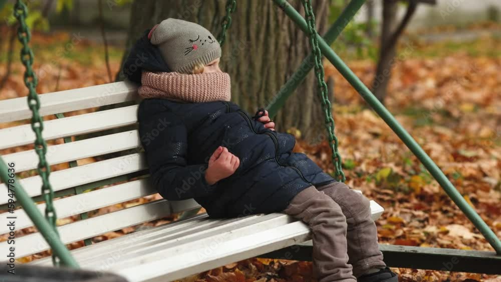 sad girl of five years sits on a bench in the park. Autumn, forest. sad girl of five years sits on a bench in the park. Autumn, forest.