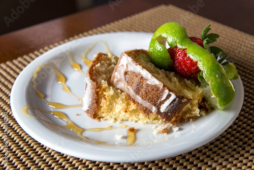 Lemon cake slice on white plate with strawberry on top,