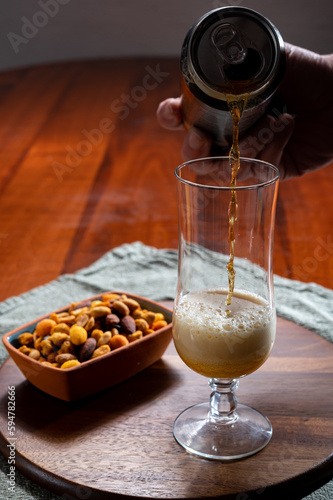 Pouring of German wheat beer is glass and bowl with party mix nuts photo