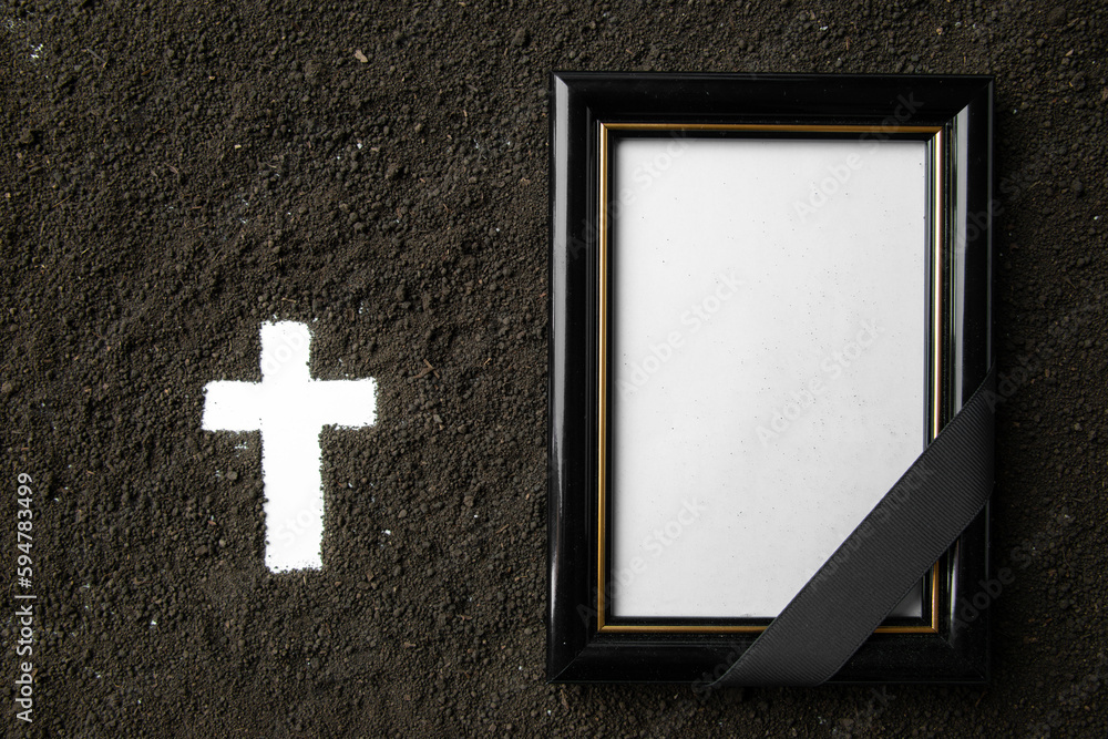 top view of white cross shape with dark soil and picture frame death grim reaper Stock Photo