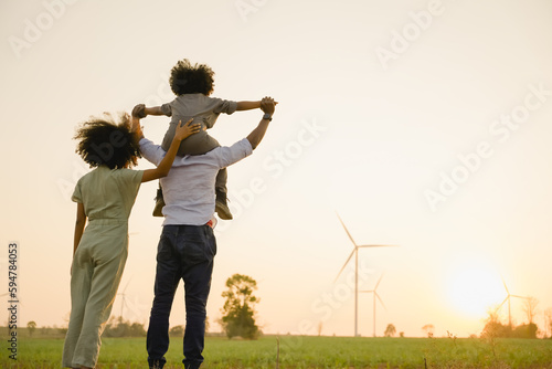 African american family in the community with wind generators turbines, Wind turbines are alternative electricity sources, the concept of sustainable resources and Renewable energy. sunset.