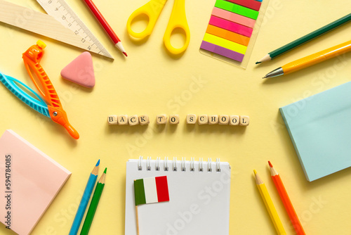 Back to school background. School accessories on a yellow background. Wooden blocks with letters