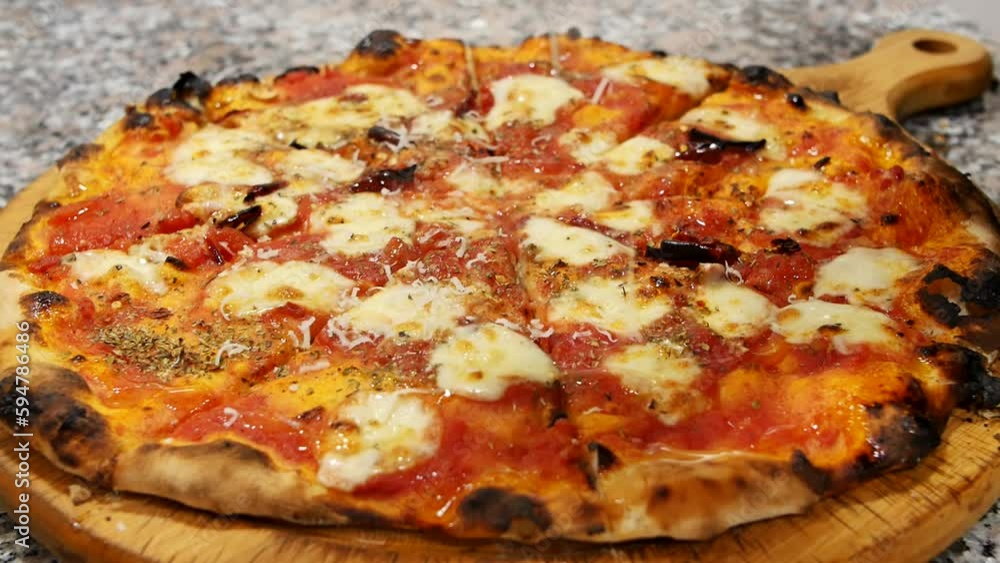 Close-up of a chef grating hard cheese on the surface of a hot pizza after baking and slicing. Particles of grated cheese falling on hot pizza and melting Close-up of a chef grating hard cheese on the surface of a hot pizza after baking and slicing. Particles of grated cheese falling on hot pizza and melting