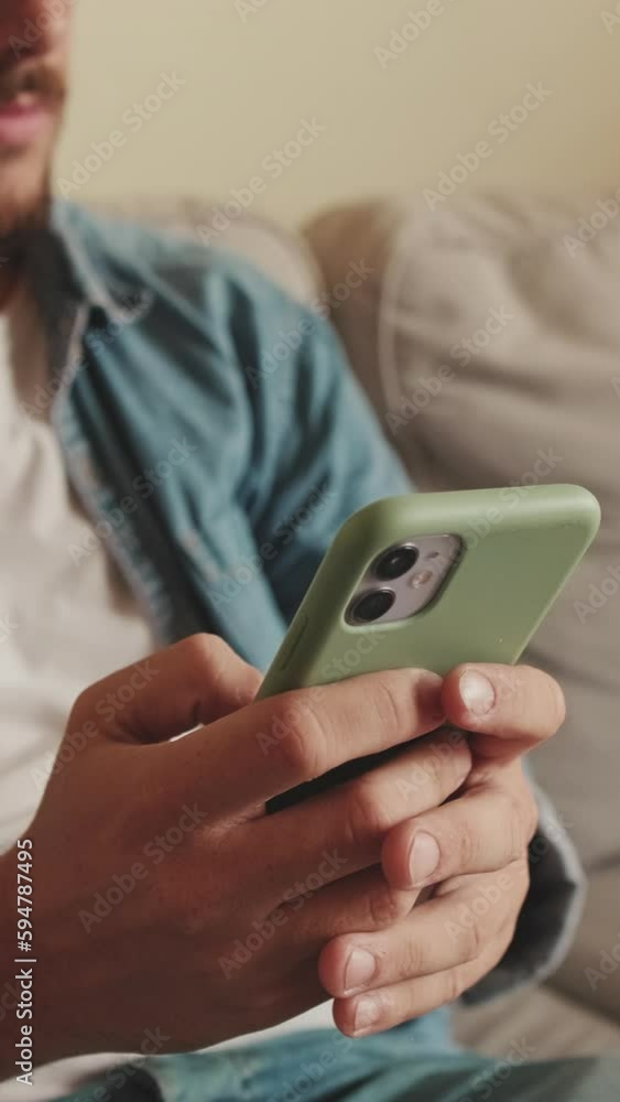 Upset man sitting on sofa using mobile phone