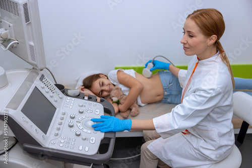 Doctor conducting ultrasound examination of kidneys to child in clinic.