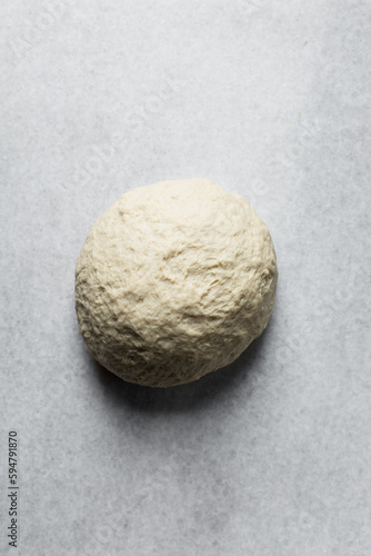 Bread dough rolled into a tight ball, bread dough resting on a marble surface