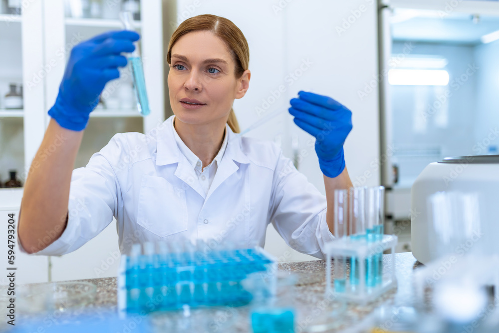 Woman researcher working with medical samples, holding test tube with blue liquid.