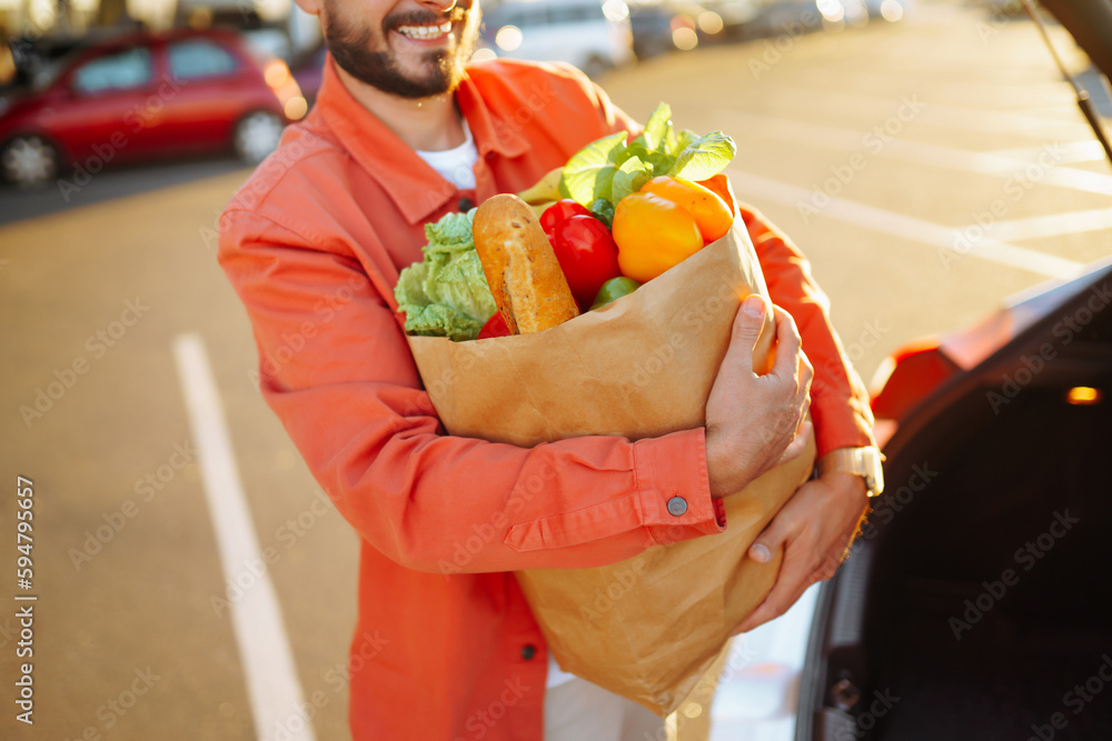 Stylish man with paper bags of vegetarian products in the parking lot near his car. Shopping for healthy vegetarian food in men's hand. Time for shopping.
Stylish man with paper bags of vegetarian products in the parking lot near his car. Shopping for healthy vegetarian food in men's hand. Time for shopping.