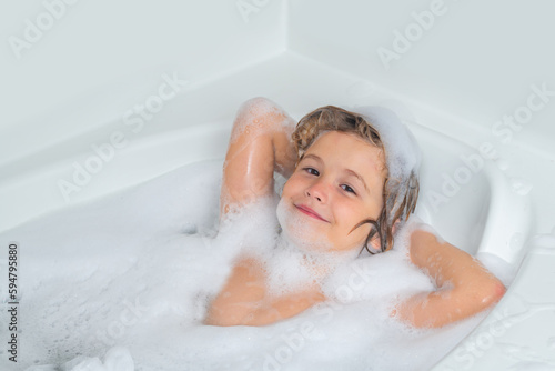 Child bathes in a bath with foam. Washing hair, kids shampoo. Foam on child head.
