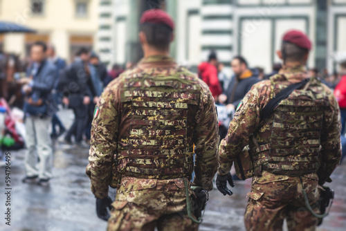 Italian armed forces squad patrol formation back view in military army uniform with red beret maintain public order and patrolling in the streets of Venice, Venezia, Italy