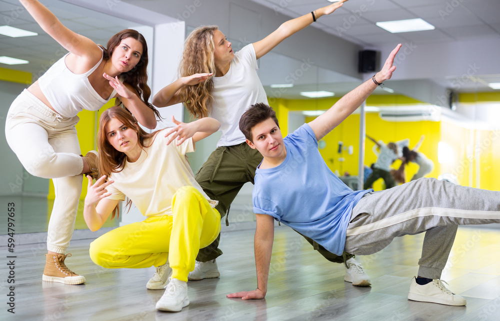 Team of positive teenagers rehearsing modern dances in dance hall
