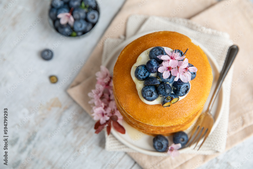 Pancakes served on a white plate with fresh fruit