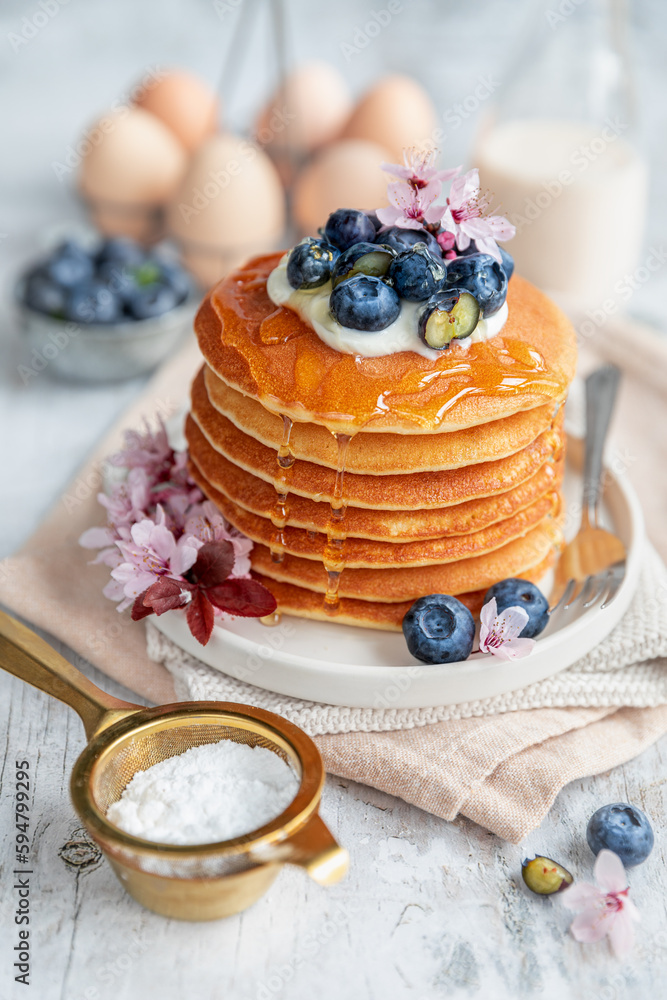 Pancakes served on a white plate with fresh fruit