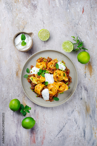 Traditional Oriental manti dumplings with spicy minced meat and yogurt served as top view on a Nordic design plate photo