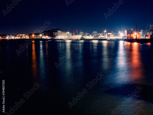 Illuminated at night Galway city port. Dockland area. Lights reflection in water. Night life. Town street with lights. West of Ireland.