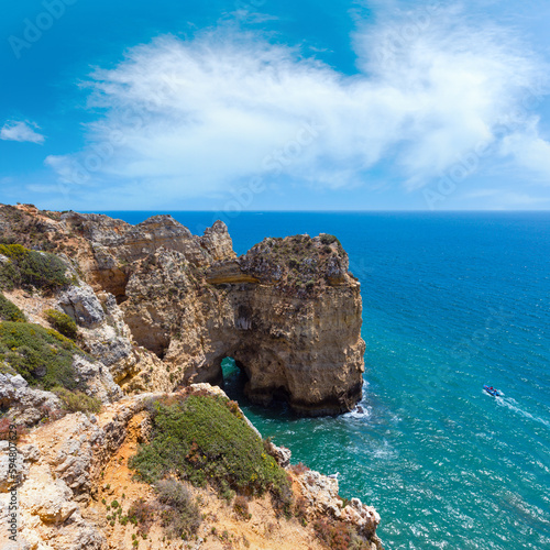 Atlantic ocean summer rocky coastline view (Ponta da Piedade, Lagos, Algarve, Portugal). People in motorboat are unrecognizable.