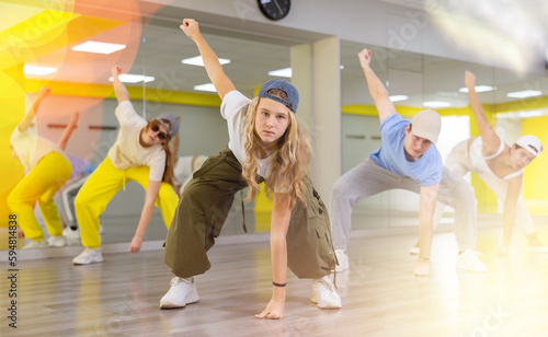 Teen girl in cap rehearses modern dances in dance hall