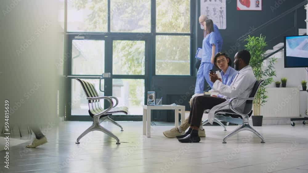 Doctor holding vitamins bottle in hospital waiting room, explaining medication treatment to asian patient during checkup visit. African american specialist discussing antibiotic prescription with man Doctor holding vitamins bottle in hospital waiting room, explaining medication treatment to asian patient during checkup visit. African american specialist discussing antibiotic prescription with man