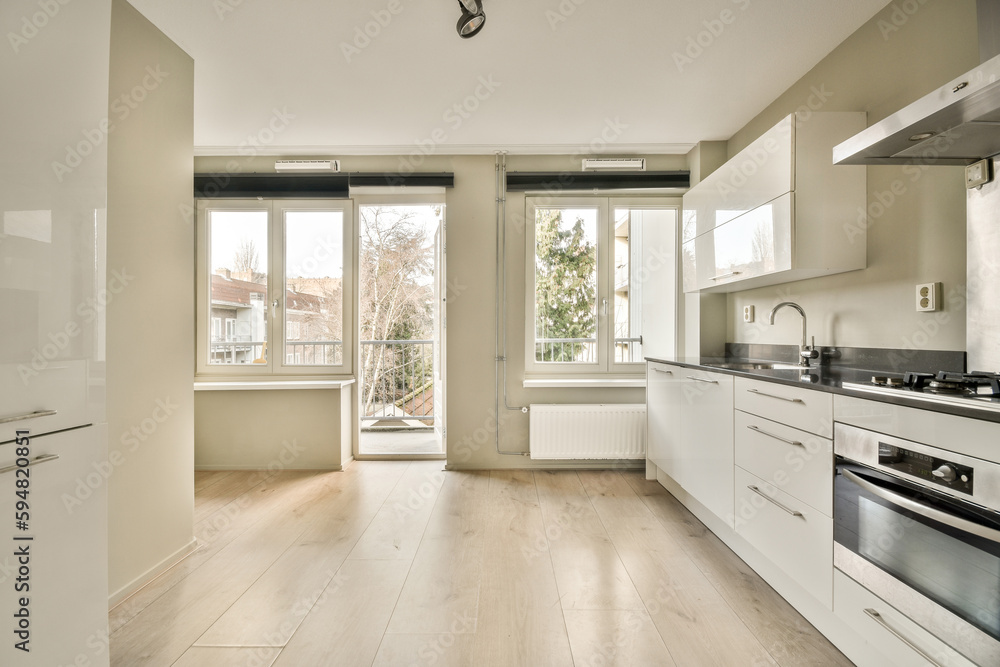 a kitchen with wood flooring and white cabinets in the middle of the room, there is a large window that looks out into