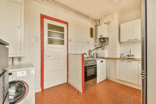 a small kitchen with an oven and dishwasher in the doord doorway leading to another room where there is a washing machine photo
