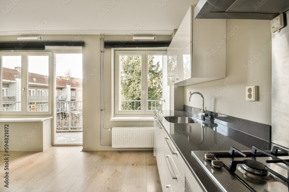 a kitchen with white cabinets and black counter tops in the center of the image is an open window that looks out onto the street a kitchen with white cabinets and black counter tops in the center of the image is an open window that looks out onto the street
