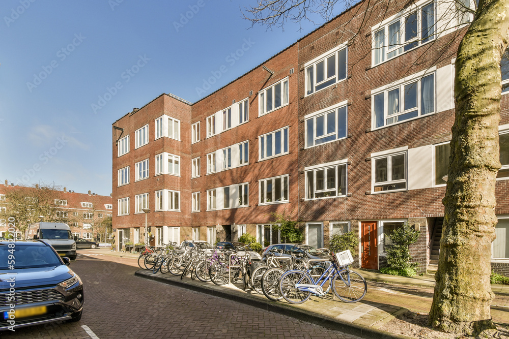 a brick building with many windows and bicycles parked on the side of the street in front of the building is clear blue sky