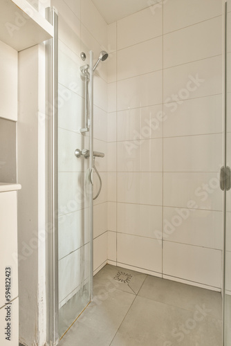 a bathroom with a shower stall in the corner and white tiles on the wall behind it, there is an open door