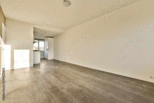 an empty living room with wood flooring and white walls on either side of the room, there is light coming through the window