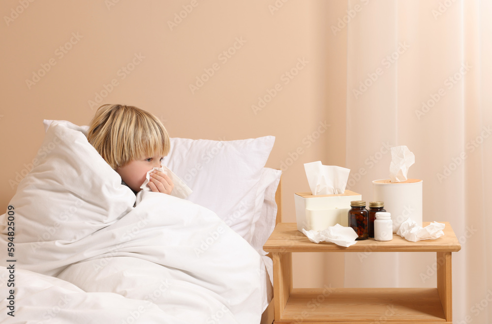 Boy blowing nose in tissue in bed at home. Cold symptoms Boy blowing nose in tissue in bed at home. Cold symptoms