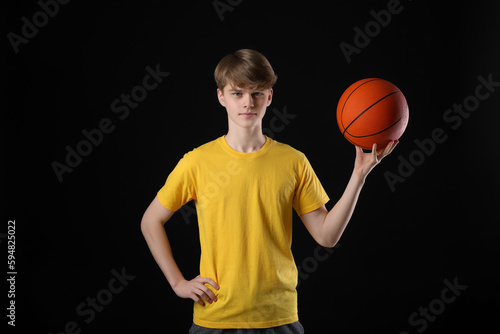 Teenage boy with basketball ball on black background © New Africa
