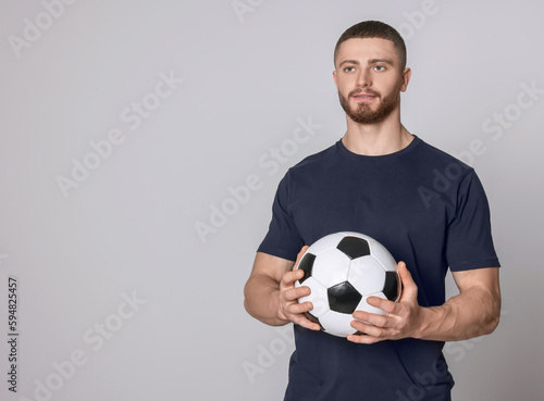Athletic young man with soccer ball on light grey background. Space for text © New Africa