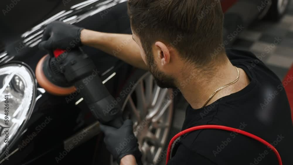 High angle shot of a mechanic polishing a black car with a polishing machine. Medium shot video. High quality 4k footage High angle shot of a mechanic polishing a black car with a polishing machine. Medium shot video. High quality 4k footage