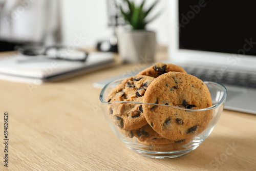 Chocolate chip cookies on wooden table at workplace. Space for text