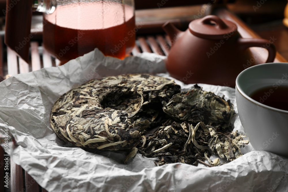 Broken disc shaped pu-erh tea on parchment paper, closeup. Traditional ceremony Broken disc shaped pu-erh tea on parchment paper, closeup. Traditional ceremony