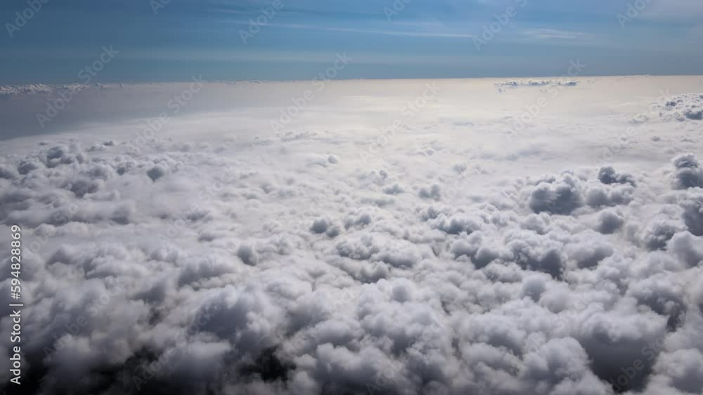 Aerial view from airplane window at high altitude of earth covered with white puffy cumulus clouds Aerial view from airplane window at high altitude of earth covered with white puffy cumulus clouds