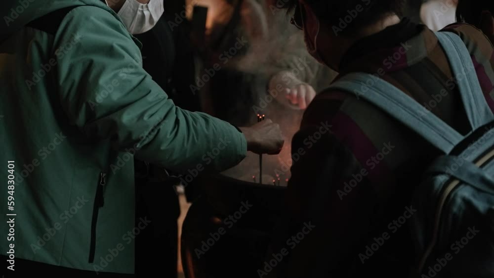 People placing incense sticks in pot at Japanese temple People placing incense sticks in pot at Japanese temple