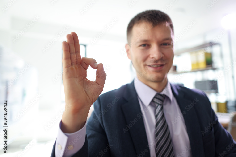 Smiling businessman shows Okay sign sitting in office Smiling businessman shows Okay sign sitting in office