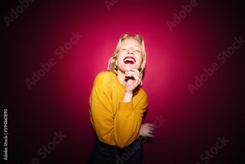 Portrait of a happy girl laughing and posing isolated on magenta background. Viva magenta, color of the year.