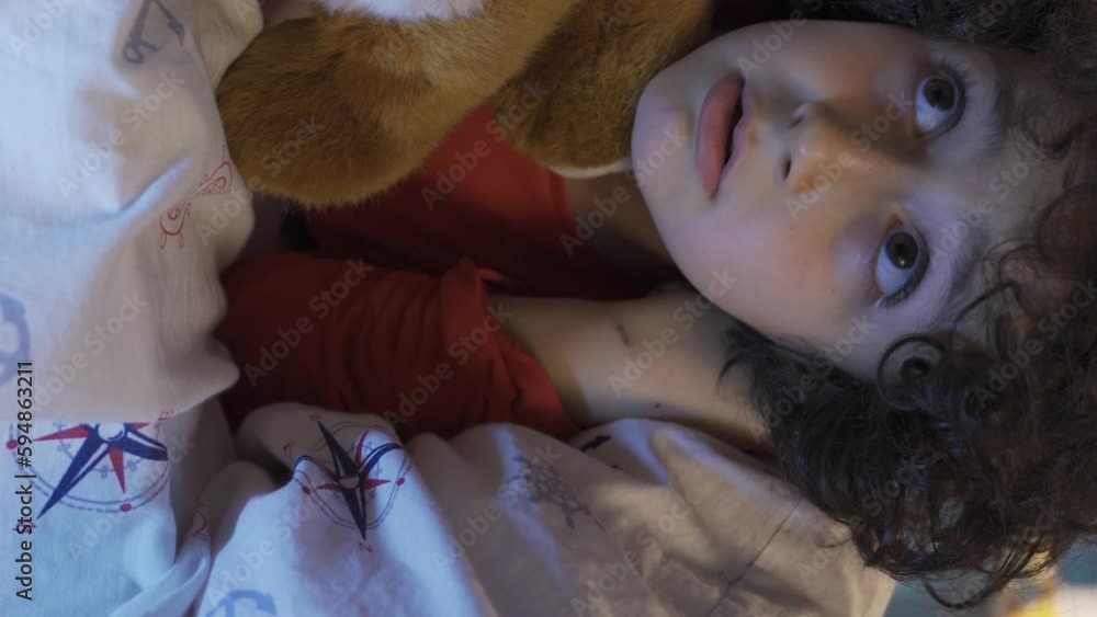 Vertical video of Cute boy hiding under the bed with his toy dog