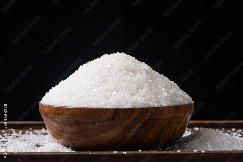 Bowls are filled with sugar on a wooden background