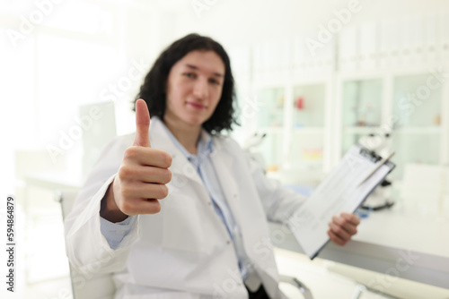 Satisfied male laboratory worker shows thumb up gesture