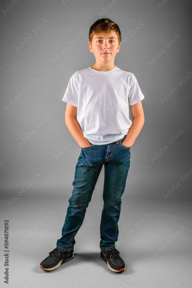 Young preteen boy in blue jeans standing posing with hands in pockets Young preteen boy in blue jeans standing posing with hands in pockets