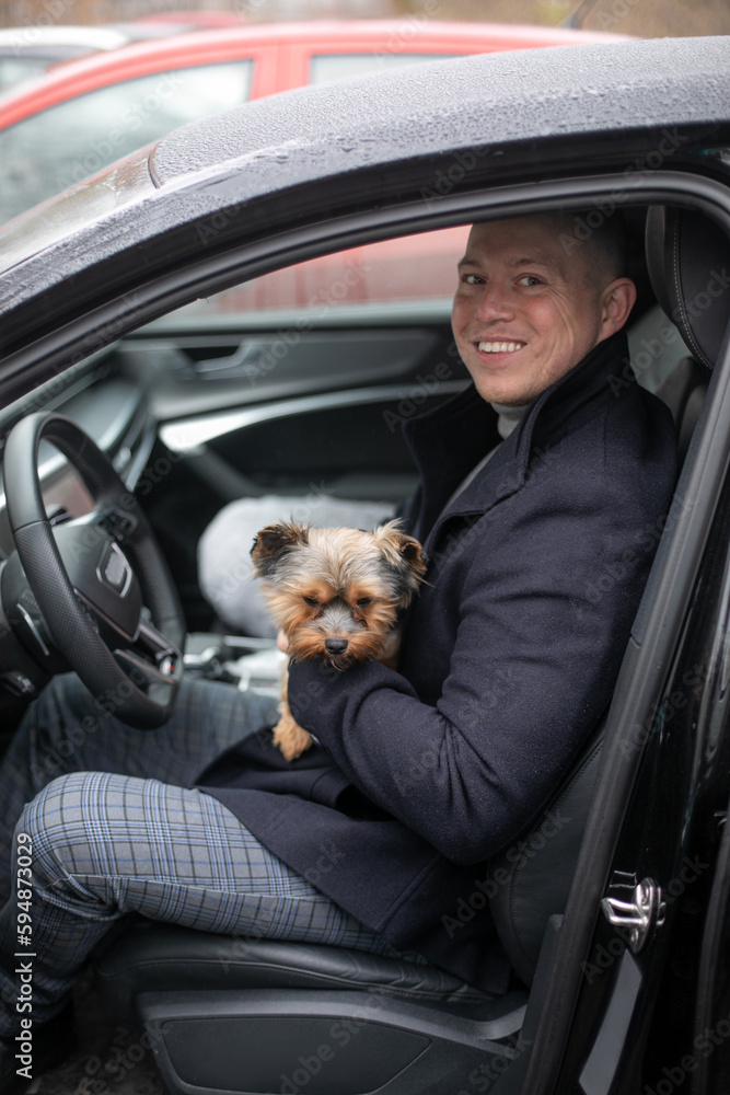 Portrait of handsome rich interesting funny intelligent man who is going to drive a car and sitting with dog 