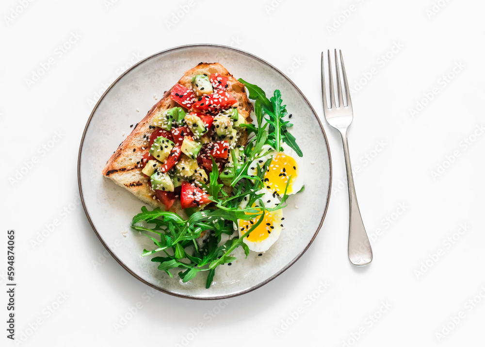Healthy breakfast, snack - avocado, tomatoes bruschetta, boiled egg and arugula on a light background, top view