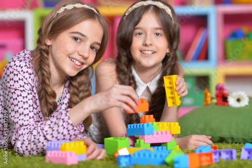 Two girls playing with colorful plastic blocks